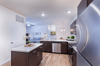 A modern kitchen with stainless steel appliances and wooden flooring.